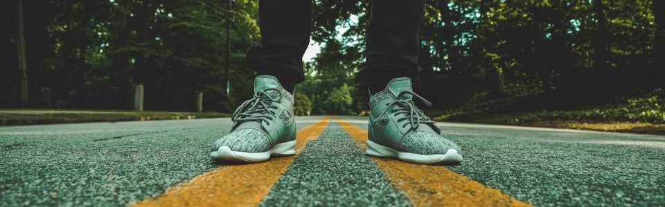 ein paar Füße in grünen Turnschuhe auf Straße und gelben Linien